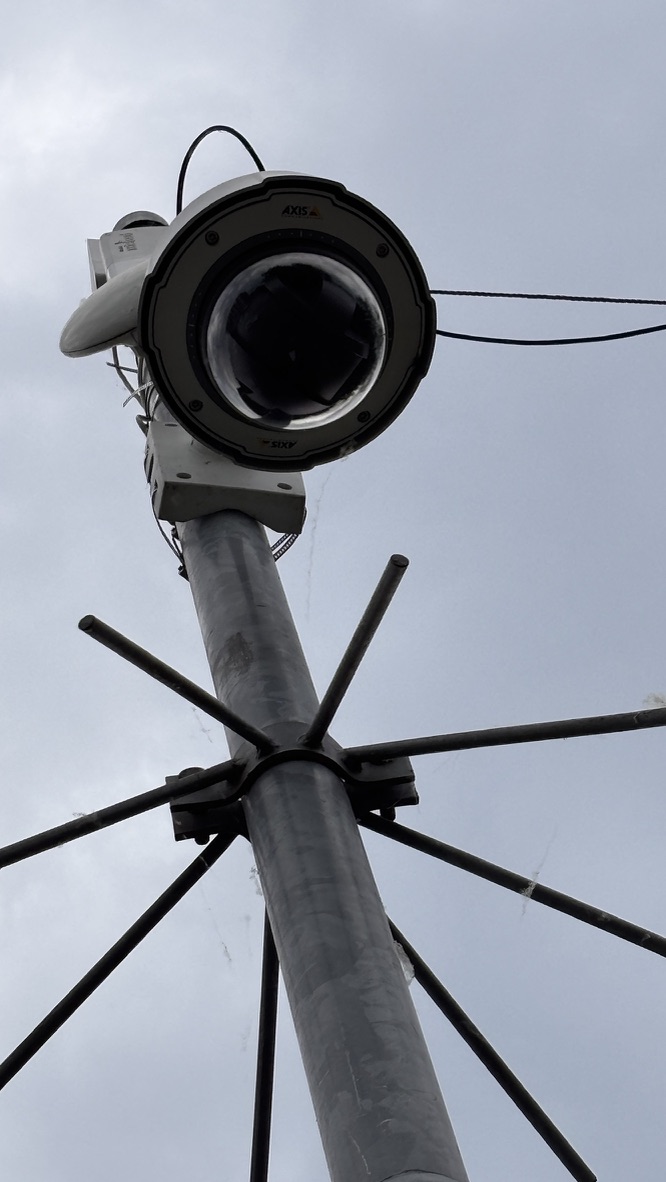 Domecamera kijkt recht omlaag vanaf een metalen mast